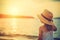 Little Girl With Straw Hat Enjoys Sunset By Water At The Beach - Generative AI