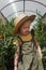 A little girl in a straw hat is picking tomatoes in a greenhouse. Harvest concept.