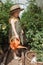 A little girl in a straw hat is picking tomatoes in a greenhouse. Harvest concept.