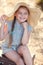 Little girl in a straw hat,resting sitting on a suitcase