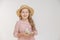 Little girl in straw hat with toy bird in hands looks at camera, concept of Easter holiday