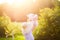 Little girl in straw hat walks and play with her toy bear in summer garden illuminated by the warm golden sunset light