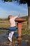 The little girl stretches to the fountain to drink water.