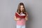 Little girl in striped T-shirt holds book, enjoys reading, standing absorbed with interesting plot.