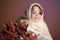 Little girl in the studio in a woolen shawl and a white coat with a branch of autumn leaves