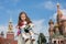 The little girl in stylish dress sitting on concrete near the Kremlin