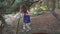 Little girl in a summer dress climbs a tree in the forest