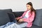 Little girl surfs on the internet sitting on the sofa