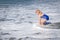 Little Girl in Swim Suit Playing in Ocean Waves at the Beach