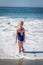 Little Girl in Swim Suite Playing in Ocean Waves at the Beach