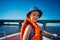 Little girl in a swimming vest sits in a motorboat