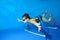 Little girl swims and plays sports underwater in the pool on a blue background, and floats through the hoops at the bottom.