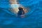 little girl swims in summer under water in the ocean, view from above