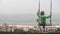 Little girl on swing overlooking Nazare ocean coast with hotels, Portugal