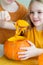 a little girl takes out a spoonful of seeds from the pumpkin for Halloween.