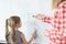 Little girl and teacher solving math equations on blackboard