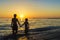 Little girl and teenager bathing on a beach at sunset