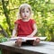 Little girl thoughtfully sitting on a bench with big book closeup view
