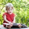 Little girl thoughtfully sitting on a bench with big book closeup view