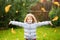 Little girl throws the autumn leaves in the air.