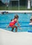 Little girl about to jump off the side of the pool during her swim lessons at the local outdoor pool in the summer