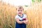 A little girl touches the hand ears of wheat in a field in summer