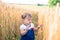A little girl touches the hand ears of wheat in a field in summer