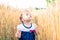 A little girl touches the hand ears of wheat in a field in summer