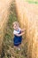 A little girl touches the hand ears of wheat in a field in summer