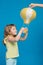 Little girl touches yellow balloon, hands raised, looks and smiles, concept of adventure and fantasy