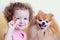 Little girl trains pomeranian spitz. beautiful little baby with curls gives to fluffy dog food, yummy. pet obedience. happy childh