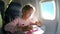 A little girl traveling by an airplane and drawing a picture with colorful pencils.