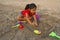 Little girl trying to make a fort with sand on Alibag beach, India