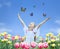 Little girl in tulips with hands up and butterfly
