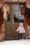 Little girl and two horses standing near the cottage door