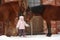 Little girl and two horses standing near the cottage door