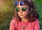 Little girl in two pairs round colored glasses