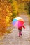 Little girl with umbrella taking walk in autumn park