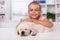 Little girl at the veterinary doctor with her puppy dog asleep on the examination table