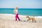 Little girl walking on the beach with a puppy terrier