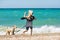 Little girl walking on the beach with a puppy terrier