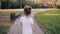 Little girl walking on a road in a park. A bun of fair hair has gold glow in the sun. Slow mo, back view