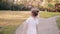 Little girl walking on a road in a park. A bun of fair hair has gold glow in the sun. Slow mo, back view