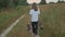 Little girl walking on a rural road with boots in her hands