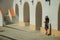 Little girl walking on sidewalk next to building with arches