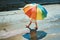 Little girl walking on sunny street after rain with colorful umbrella