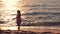 Little girl walking at sunrise on beautiful ocean beach. Happy summer vacation