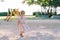 Little girl walks along the playground to a colorful slide. Back view