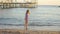 little girl walks along seashore, collects stones and throws them into water.