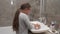 Little girl washes hands under running water in bathroom